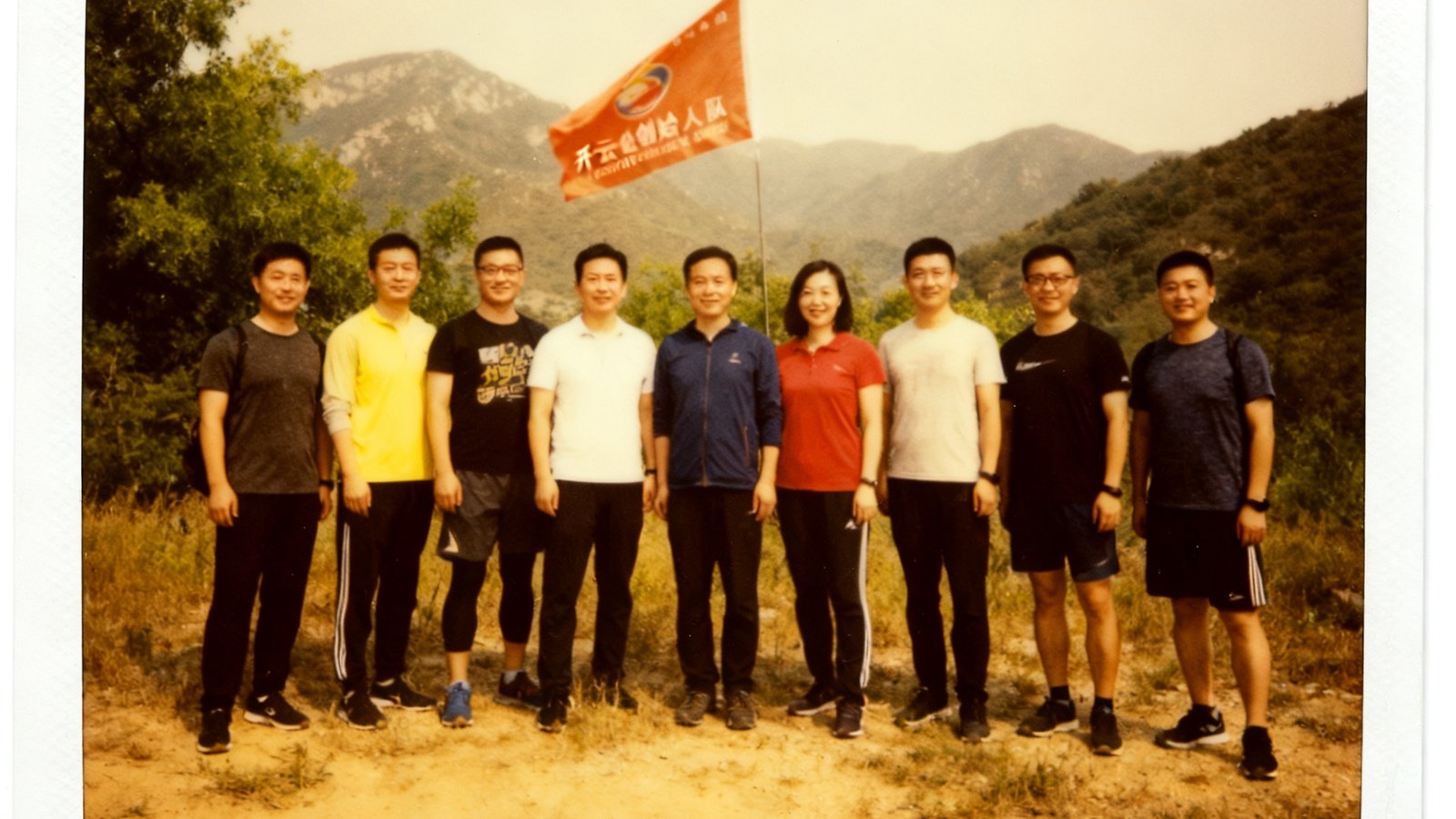 开云创始人团队在2018年第一次社区徒步活动中的合影，背景是山野和队旗，展现创业初心